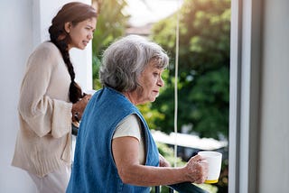 Women looking outside their window, holding cups of tea