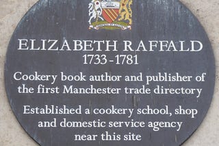 Bronze circular plaque with colourful coat of arms at head and details of Elizabeth Raffald printed in white.