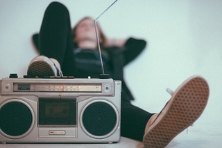 Person lying down with an old school radio next to them