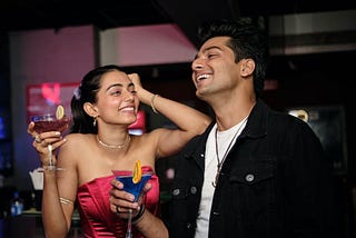 A similar looking guy and girl laughing in a bar