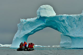 A boat beneath an iceberg’s arch, hinting at the vast hidden bulk, much like the pivotal, untested sliver in software’s depth.