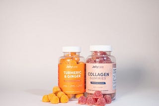 A jar with orange tumeric and ginger gummies and a second jar with red collagen gummies.