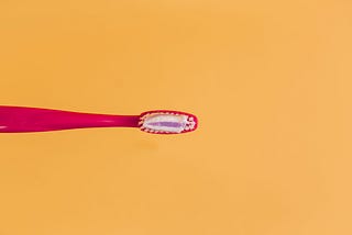 Red toothbrush on contrasting orange background