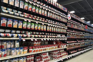 The soup aisle in a grocery store, depicting several shelves with cans of various soups.