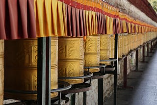 A colour image of a long line of Buddhist prayer wheels against a wall