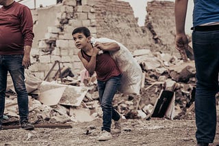 A young boy walks past buildings destroyed in a rocket attack on Ganja, Azerbaijan’s second city. Image: Orkhan Rahmanli