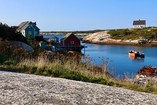 A charming harbor with a couple of houses and a small boat anchored in the calm water.