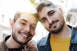 Two close male friends with their arms around each other.