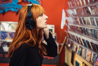 Young woman listening to music and looking at CDs in a music shop