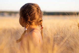 girl wearing pink camisole in the midst of brown plants during daytime