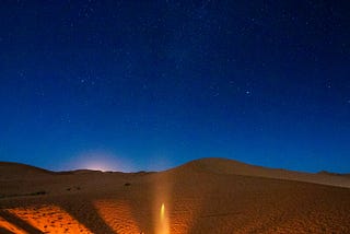 People sitting in a campfire under the night sky.