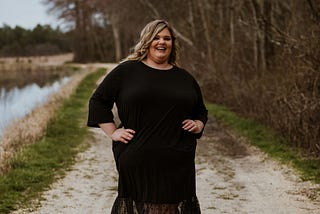 A smiling fat woman in a black dress.