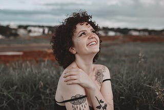 Photo shows a young woman, seemingly happy to just be in a field.