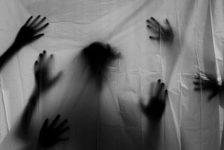 A transparent sheet with the silhouette of a head and multiple hands trying to reach through to the other side.