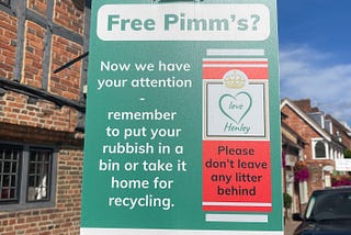 A street sign in Henley in South Oxfordshire, England. It’s on a green rectangular background. It says “Free Pimm’s? Now we have your attention. Remember to put your rubbish in a bin or take it home for recycling.” There is a motif of a red Pimm’s can which says “Love Henley. Please don’t leave any litter behind.”