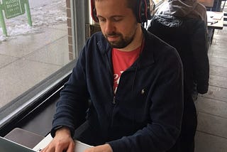 Spenser Warren at his laptop computer writing in a coffee shop.