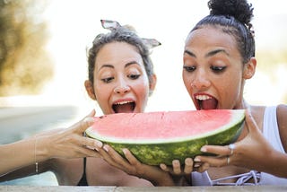 Women gorging on a huge chunk of watermelon