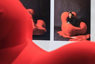 A photo from an exhibition of a woman sitting on Gaetano Pesco’s UP series chair