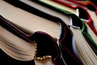 stack of rainbow-colored books, spines forced open, maybe on a discard pile