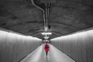 Person wearing red jacket and backpack in a subway