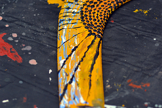 Boomerang — yellow with paint splattered on a black background