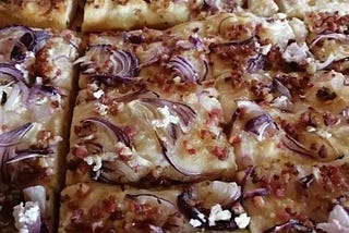 A close up of the dish with melted cheese and red onions on top.