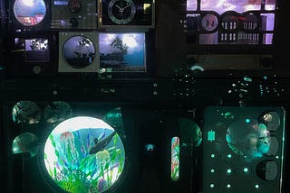 An image from Meow Wolf’s Convergence Station in Denver, Colorado, of a wall of vaguely technical-looking gadgets and readouts from the 1970s, including meters with needles, clocks, a mini-diorama, and a small artificial aquarium.