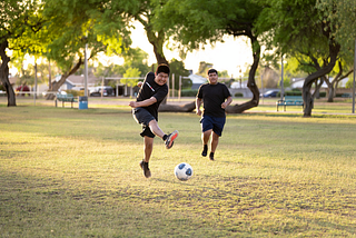 Two brothers spend quality time together playing soccer in the fields of Mitchell Park in Tempe, Ariz.