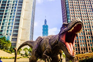A Tyrannosaurus Rex is in a city, roaring it up