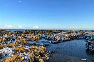 Rocky shoreline with frosted vegetation and semi frozen rock pools