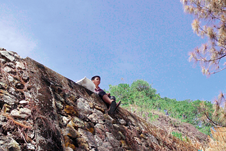 A still photo from the film, Game Boy Advance, featuring a young boy sitting atop a stone wall.