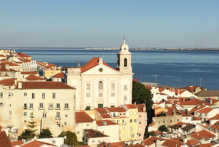 Red-roofed white houses in Lisbon, with the sea in the background
