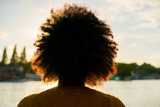 A black woman dreaming with her eyes opened looking at the sky.