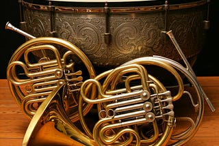 A timpani drum and sticks with two French horns poised in front.