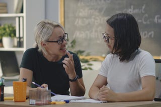 Two teachers talking in a classroom.