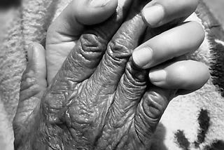 An old person’s hand in a young person’s hand.