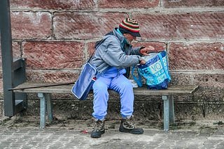 homeless man digging through shopping bag