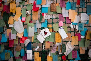colorful paper tags with handwritten messages hanging from a wall
