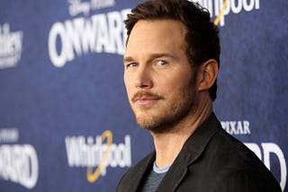 A photo of Chris Pratt wearing a black suit at the premier of the Pixar movie Onward.