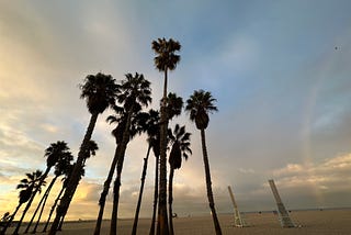 Palm trees, beach, rainbow, and interesting clouds in Santa Monica, CA.