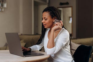 A Woman Holding a Credit Card While Using a Laptop.