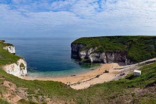 View of North Landing, Flamborough, Yorkshire, UK — chalk headlands either side with sandy bay on a sunny day.