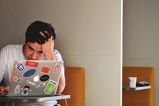 Man with his head in his hand, staring at a laptop