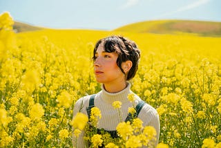 A woman sitting in a field of yellow flowers