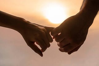 Romantic partners holding hands with the sunset behind them