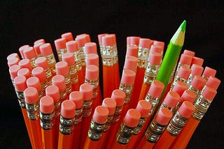 One green pencil amongst red ones. Odd one out. Barbara Cook blogger