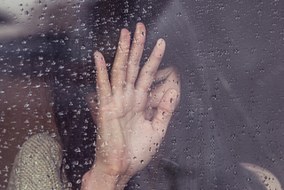 sad woman leaning against glass window