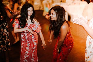 Two latinas smile while dancing How to Learn to Cumbia by Jim Latham | Photo by Omar Lopez on Unsplash