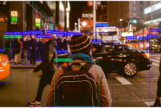 An image of a busy city street at night, with persons and cars being detected by YOLO-NAS.