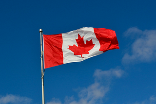 The Canadian flag in front of the blue sky